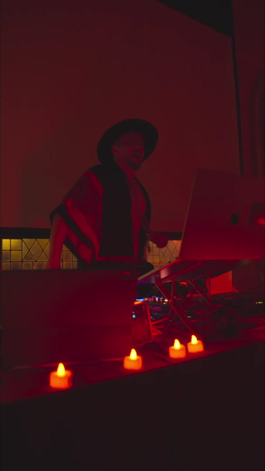 Sasha at the decks in the red-lit dance space